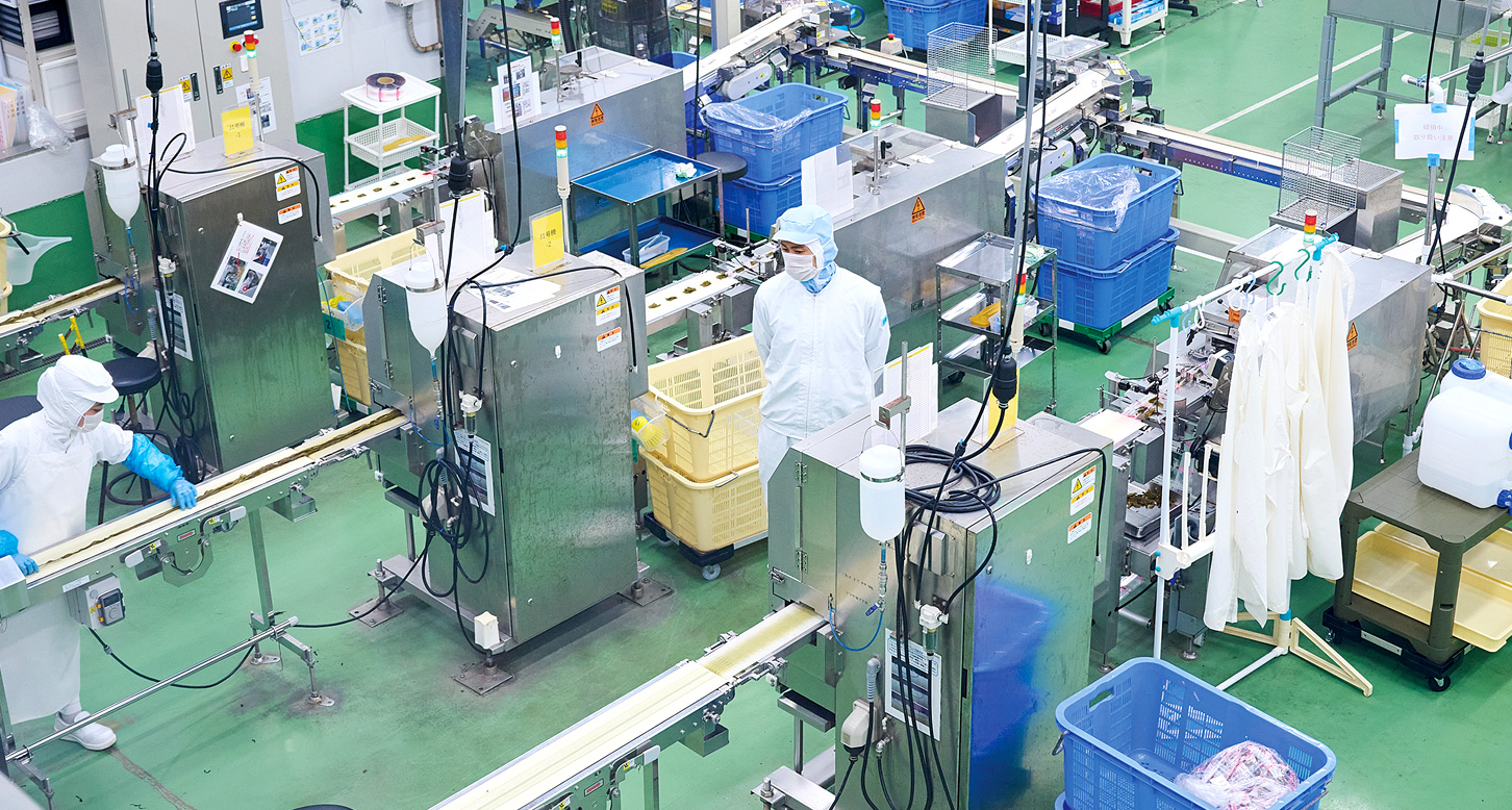 機械で作業するスタッフを見守る小林さん