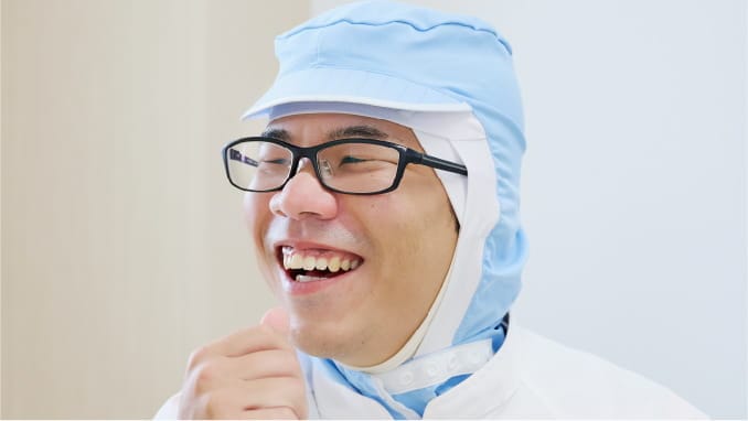 工場の白い作業服を着た笑顔の男性
